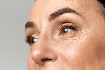 Cropped portarit of beautiful middle-aged woman with healthy, natural condition skin looking away...