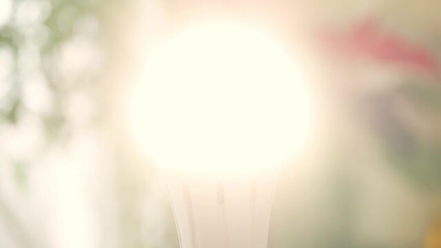 One Person Screws a Led Light Bulb in the Socket and Turn On the Light in the Room. Saving Energy Concept Using Led Bulb.