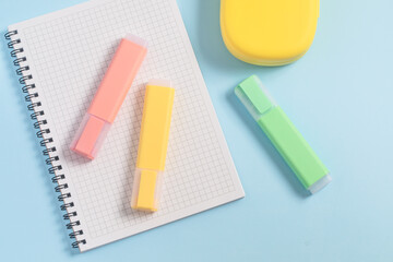 School supplies, back to school, multi-colored markers and notebooks on a blue background