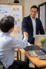 A professional Asian businessman is shaking hands with a male employee during the meeting.