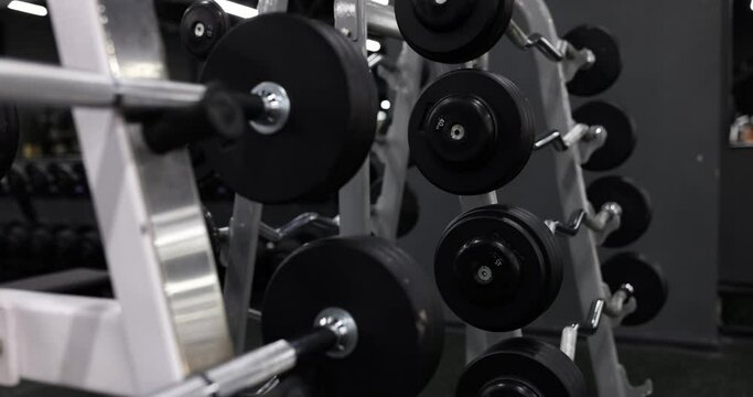 Closeup of chrome steel bar with black weight plate on machine in gym. Body workouts and fitness for healthy lifestyle