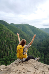 Naklejka premium Beautiful woman with backpack admires view from top of mountain. Mountain tourism. Girl traveler on background of mountains. Active lifestyle.