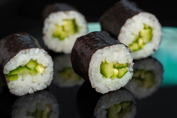 Sushi rolls with seaweed on black background.