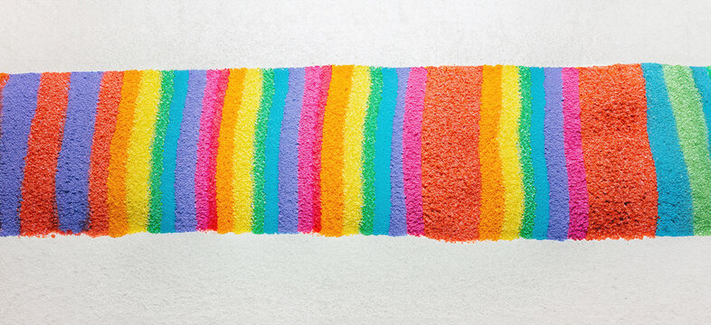 immagine con banda di sabbia colorata nei toni arcobaleno, colori luminosi e brillanti su sfondo bianco
