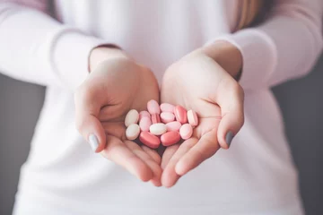 Fotobehang Young woman holding several vitamin pills and supplements in her hands © Maris