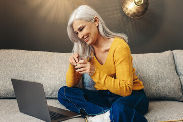 Senior woman working remotely from her couch at home