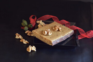 turrón de nueces y chocolate con fondo oscuro con cinta roja con enfoque selectivo