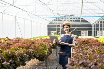 Asian female farmers use computers to collect data and monitor the quality and quantity of...