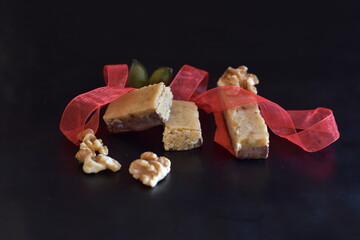 turrón de nueces y chocolate con fondo oscuro con cinta roja con enfoque selectivo