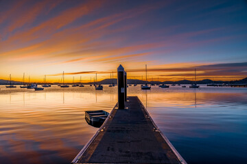 Sunrise at the jetty with high cloud and boats on the water