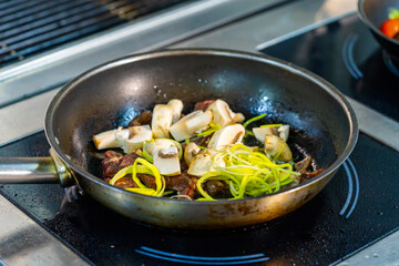 A frying pan filled with food on top of a stove. Delicious meal cooking on a stovetop in a frying pan