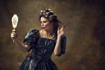 Princess. Portrait of young woman dressed in black dress made of garbage bags curls hair with paper...