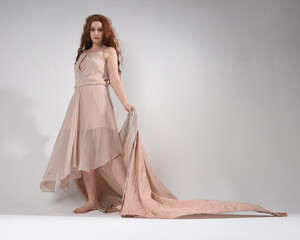 Full length portrait of beautiful brunette female model with   wearing a creamy pink gown dress....