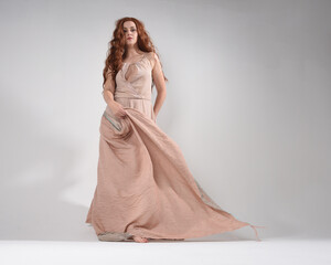 Full length portrait of beautiful brunette female model with   wearing a creamy pink gown dress....