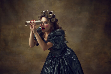 Queen. Portrait woman wearing black dress made of garbage bags curls hair with paper tubes...