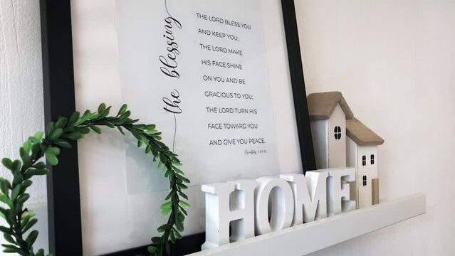 Composition of decor on a white background with a frame, a Christian verse from the Bible and wooden figurines of a house