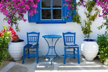 traditional greek home outdoor scenery with front yard, greek style table and chairs and blooming flowers and bougainvillea