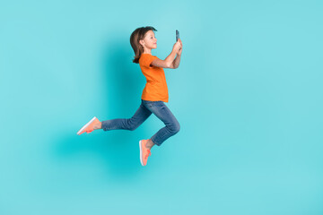 Fototapeta na wymiar Photo of charming positive girl wear stylish orange clothes fly air use phone photographing selfie isolated on cyan color background