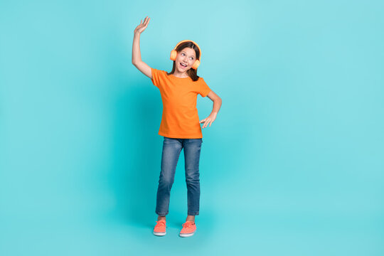 Full length photo of cheerful optimistic girl wear stylish orange clothes have fun look empty space ad isolated on cyan color background