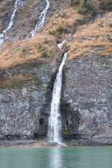 Melt water waterfall down the side of a snow covered mountain,  Alaska, USA