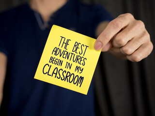 Teacher hand holding a yellow stick note with a classroom message, a business back-to-school concept