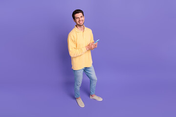Full body photo of young guy blog owner write his content plan use apple iphone wear trendy long sleeve isolated on purple color background