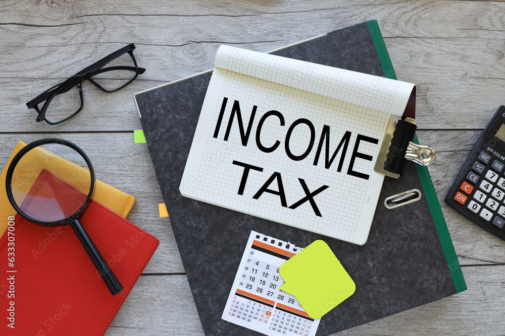 Poster income and tax text on a notebook on a folder. red notepad. magnifying glass