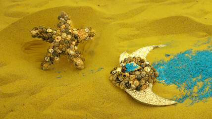 sea star and fish made of little seashells on the yellow sandy background minimal summer creative concept flat lay.