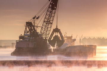 Grab dredger near the barge dumps soil from the bottom of the sea onto the barge - obrazy, fototapety, plakaty