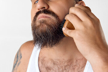 Cropped image of male face, man taking care after beard with special brush against white studio background. Concept of men's beauty, skin care, cosmetology, health and wellness. Copy space for ad