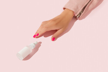 Womans hands with serum dropper on pink background. Body care beauty treatment concept
