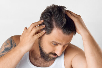 Fototapeta premium Trichologist care. Bearded mature man showing hair condition on white background. Hair loss, vitamins, growth. Concept of men's beauty, skin care, cosmetology, health and wellness. Copy space for ad