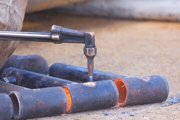 Focus at the acetylene gas welding torch is drilling hole on galvanized steel pipes to fixing bolts...