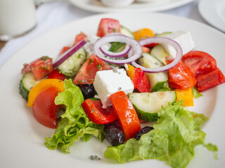 fresh salad with onion, tomato, cheese on the white plate in tatar restaurant in capital kyiv