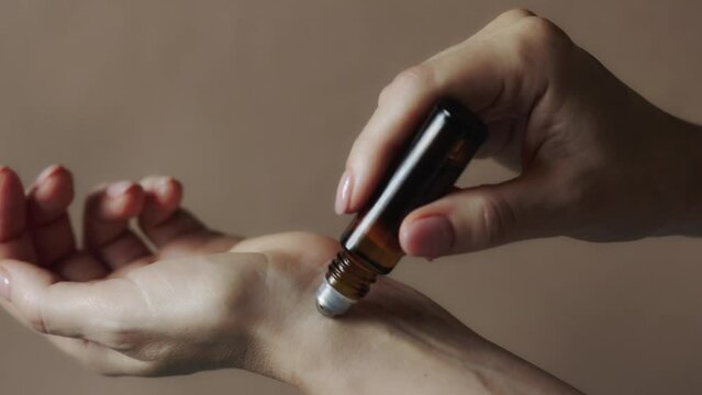 Woman applying natural rollerball aroma oil on her wrist close up
