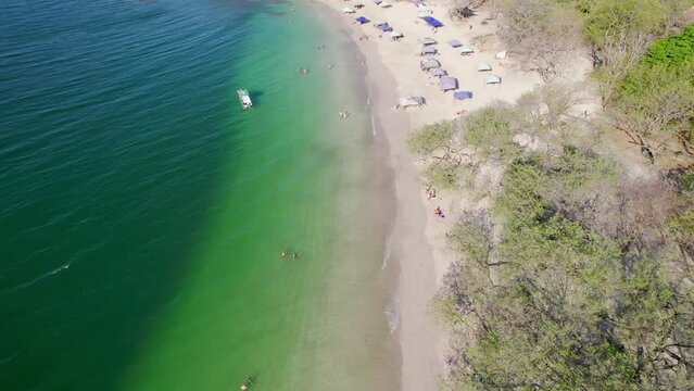 4K Aerial Drone Flyover Popular Tourist Destination Tropical Conchal Beach Costa Rica With People And Beach Tents On Shore