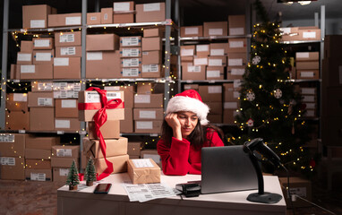 Tired santa claus stressed working in warehouse fast delivery of christmas parcels, e-commerce and small business concept