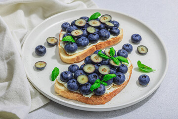 Fresh bread sandwiches with sweet blueberries, cream cheese and basil leaves. Good morning concept