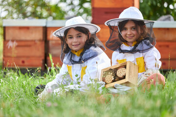 Smiling girls sitting with wooden insect hotel
