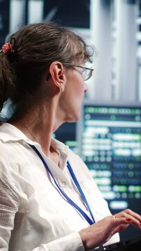 Vertical video Adept computer scientist looking around cutting edge data center, preparing to start comission on defective high tech server mainframes in order to ensure secure operations