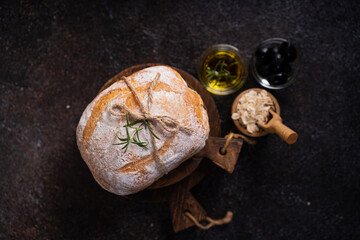 Fresh organic homemade artisan ciabatta bread with herbs, olive oil and olives on dark rustic...
