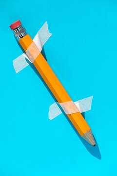 Yellow pencil stuck with adhesive tape on blue wall