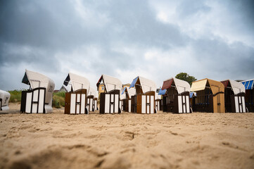 Roofed wicker beach chairs at the baltic sea beach, coast at the island of Usedom in Germany, storm...