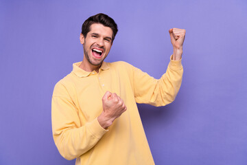 Photo of overjoyed satisfied person raise fists triumph accomplishment scream yeah isolated on violet color background