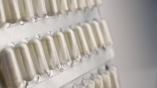 Silver blister pack with white pharmaceutical capsules, rotation in circle. white capsules in a blister, Turning. selective focus. Virus medication concept. vitamin, Medicine chest. vertical vide     