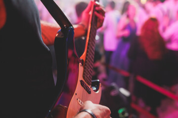 Concert view of an electric guitar player with vocalist and rock band performing in a club, male...