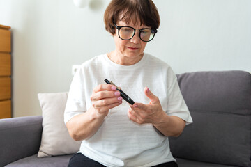 Woman measures blood sugar glucose meter, diabetes concept. Diabetic mature woman write blood...