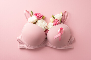 Promote breast cancer awareness. Top view of pink ribbon attached to bra filled with delicate...