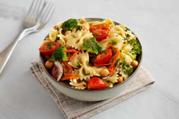 Yummy Homemade Vegan Pasta Salad with Tomato, Onion, Carrot, Broccoli, Chickpeas and Parsley in a Bowl, side view.