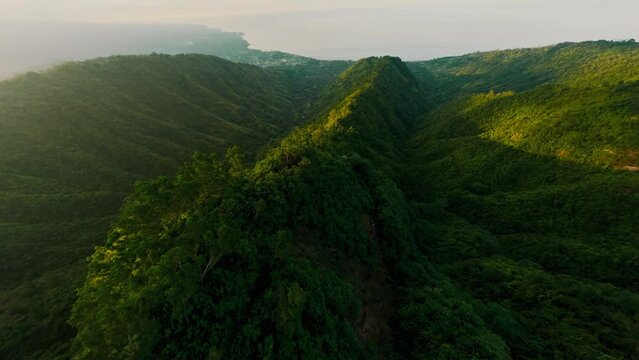 Aerial dive view flight over mountain ridge covered by green plant at sunlight sea ocean lagoon landscape. FPV sport drone shot picturesque Asian natural geology formation cliff rock over seascape 4k